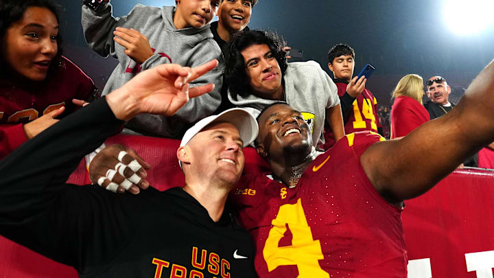 Nov 29, 2025; Los Angeles, California, USA; Southern California Trojans head coach Lincoln Riley (right) and defensive tackle Jahkeem Stewart (4) pose with fans after the game against the UCLA Bruins at United Airlines Field at Los Angeles Memorial Coliseum. 
