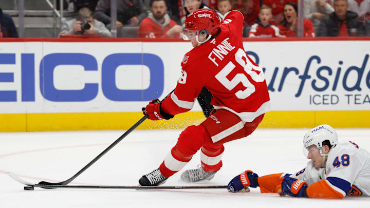 Dec 16, 2025; Detroit, Michigan, USA;  Detroit Red Wings center Emmitt Finnie (58) skates with the puck defended by New York Islanders defenseman Matthew Schaefer (48) in the second period at Little Caesars Arena. Mandatory Credit: Rick Osentoski-Imagn Images
