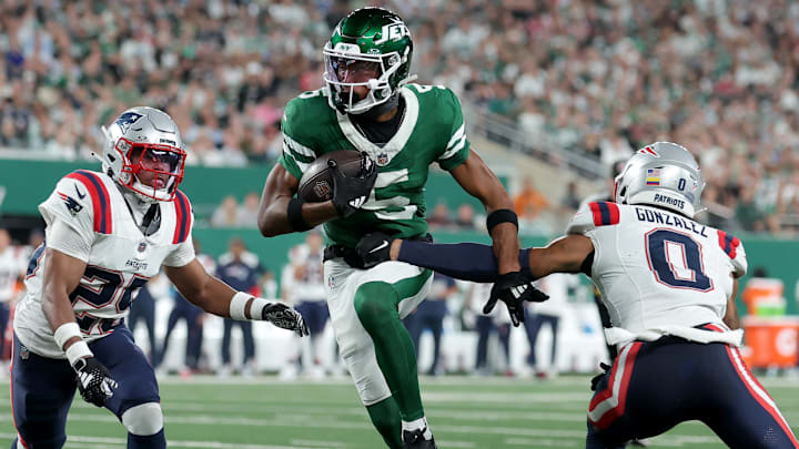 Sep 19, 2024; East Rutherford, New Jersey, USA; New York Jets wide receiver Garrett Wilson (5) runs with the ball against New England Patriots cornerbacks Marcus Jones (25) and Christian Gonzalez (0) during the third quarter at MetLife Stadium. Mandatory Credit: Brad Penner-Imagn Images