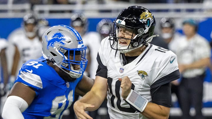 Nov 17, 2024; Detroit, Michigan, USA; Jacksonville Jaguars quarterback Mac Jones (10) passes the ball and is pressured by Detroit Lions defensive end Levi Onwuzurike (91) during the second half at Ford Field. Mandatory Credit: David Reginek-Imagn Images