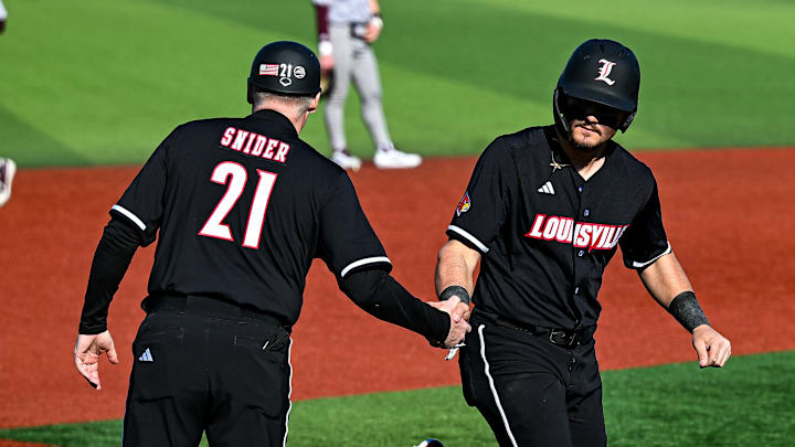 Louisville third base coach Eric Snider congratulates first baseman Tague Davis as he rounds the bases after hitting a home run. Louisville third base coach Eric Snider congratulates first baseman Tague Davis as he rounds the bases after hitting a home run.