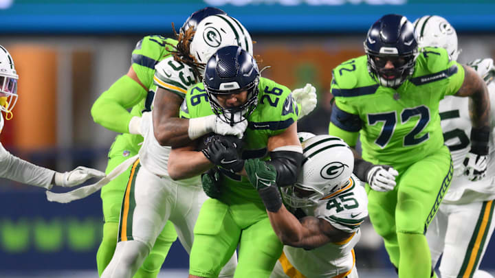 Dec 15, 2024; Seattle, Washington, USA; Green Bay Packers defensive end Arron Mosby (53) and Green Bay Packers linebacker Eric Wilson (45) tackle Seattle Seahawks running back Zach Charbonnet (26) during the second half at Lumen Field. Mandatory Credit: Steven Bisig-Imagn Images
