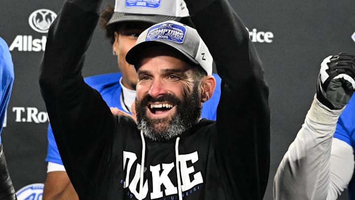 Dec 6, 2025; Charlotte, NC, USA; Duke Blue Devils head coach Manny Diaz lifts the ACC trophy with offensive lineman Justin Pickett (77) and defensive tackle Aaron Hall (99) after defeating the Virginia Cavaliers at the 2025 ACC Championship game at Bank of America Stadium. Mandatory Credit: Bob Donnan-Imagn Images