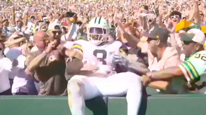 Green Bay Packers running back Josh Jacobs does the Lambeau Leap to celebrate a touchdown.