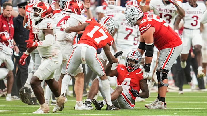Ohio State Buckeyes wide receiver Carnell Tate (17) and offensive lineman Luke Montgomery (51) help up wide receiver Jeremiah Smith (4) after the final play in the Big Ten Conference championship game against the Indiana Hoosiers at Lucas Oil Stadium in Indianapolis on Dec. 6, 2025. Ohio State lost 13-10. Ohio State Buckeyes wide receiver Carnell Tate (17) and offensive lineman Luke Montgomery (51) help up wide receiver Jeremiah Smith (4) after the final play in the Big Ten Conference championship game against the Indiana Hoosiers at Lucas Oil Stadium in Indianapolis on Dec. 6, 2025. Ohio State lost 13-10.