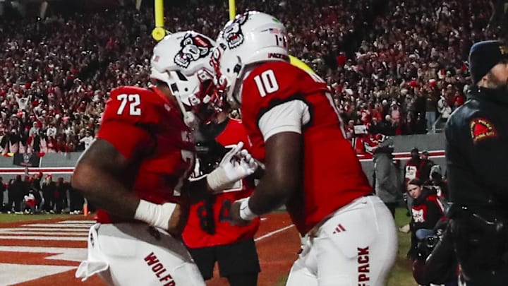 Nov 29, 2025; Raleigh, North Carolina, USA;  NC State Wolfpack quarterback Will Wilson (10) makes a touchdown and celebrates with offensive lineman Spike Sowells Jr. (72) during the first half of the game against North Carolina Tar Heels at Carter-Finley Stadium.  Mandatory Credit: Jaylynn Nash-Imagn Images