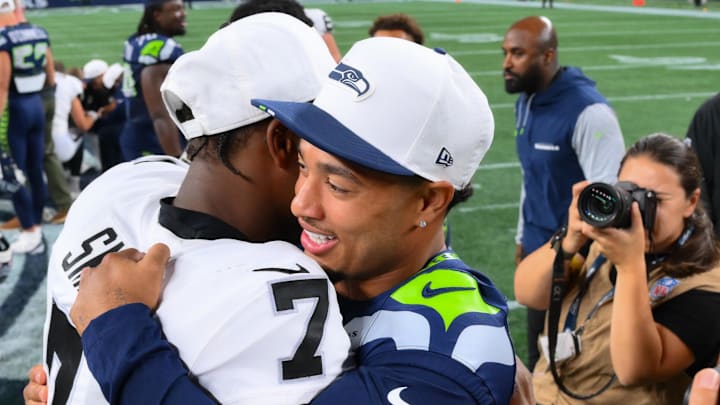 Aug 7, 2025; Seattle, Washington, USA; Las Vegas Raiders quarterback Geno Smith (7) and Seattle Seahawks wide receiver Jaxon Smith-Njigba (11) hug after the game at Lumen Field. Mandatory Credit: Steven Bisig-Imagn Images