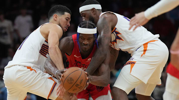 Miami Heat forward Jimmy Butler (22) tries to drive between Phoenix Suns guard Devin Booker (left) and forward Royce O'Neale (right) during the second half at Kaseya Center.
