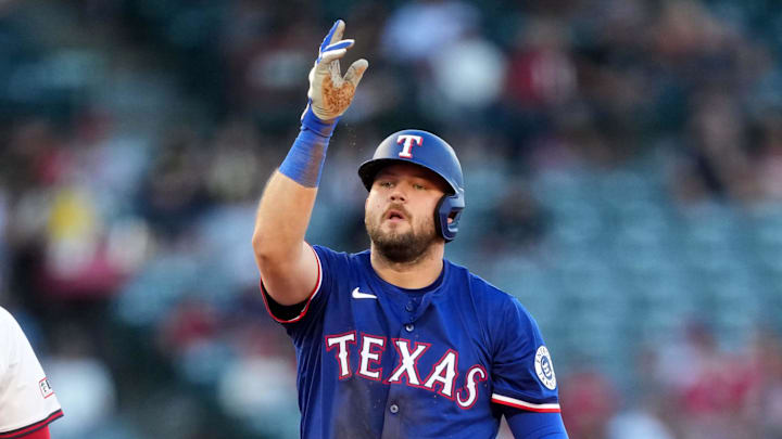 Jul 10, 2025; Anaheim, California, USA; Texas Rangers first baseman Jake Burger (21) gestures after hitting a RBI double in the third inning as Los Angeles Angels second baseman Luis Rengifo (2) watches at Angel Stadium. 