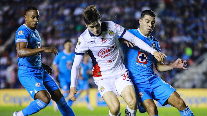 Armando González de Chivas defiende el esférico de Erik Lira y el colombiano Willer Ditta, ambos de Cruz Azul