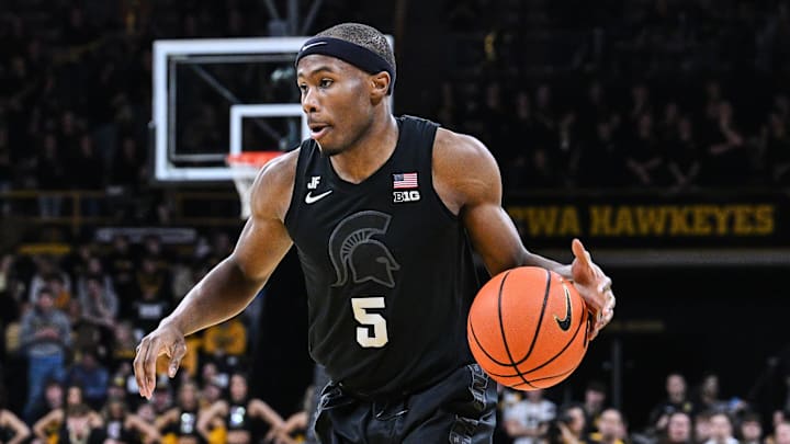 Mar 6, 2025; Iowa City, Iowa, USA; Michigan State Spartans guard Tre Holloman (5) controls the ball as Iowa Hawkeyes forward Payton Sandfort (20) defends during the first half at Carver-Hawkeye Arena. Mandatory Credit: Jeffrey Becker-Imagn Images