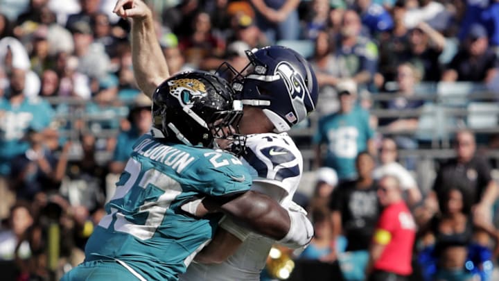 Oct 12, 2025; Jacksonville, Florida, USA; Seattle Seahawks quarterback Sam Darnold (14) is tackled by Jacksonville Jaguars linebacker Foye Oluokun (23) during the second half at EverBank Stadium. Mandatory Credit: Travis Register-Imagn Images