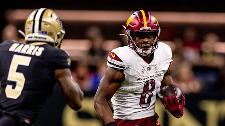 Dec 15, 2024; New Orleans, Louisiana, USA;  Washington Commanders running back Brian Robinson Jr. (8) rushes against New Orleans Saints cornerback Will Harris (5) during the first half at Caesars Superdome. Mandatory Credit: Stephen Lew-Imagn Images