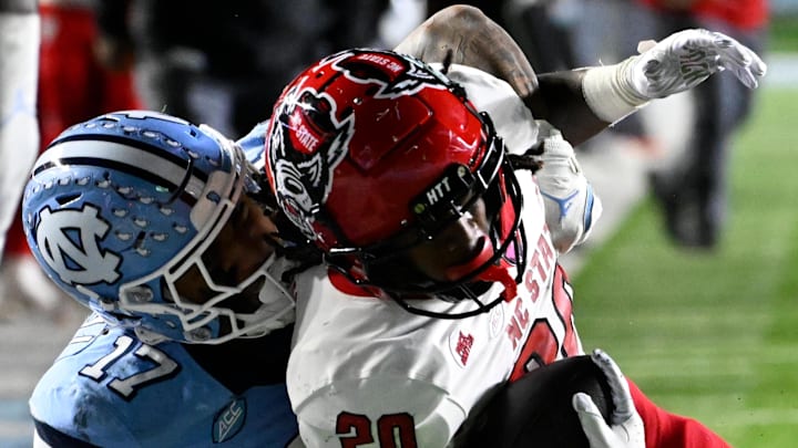 Nov 30, 2024; Chapel Hill, North Carolina, USA; North Carolina State Wolfpack running back Hollywood Smothers (20) is tackled near the goal line by North Carolina Tar Heels linebacker Amare Campbell (17) late in the fourth quarter at Kenan Memorial Stadium. Mandatory Credit: Bob Donnan-Imagn Images