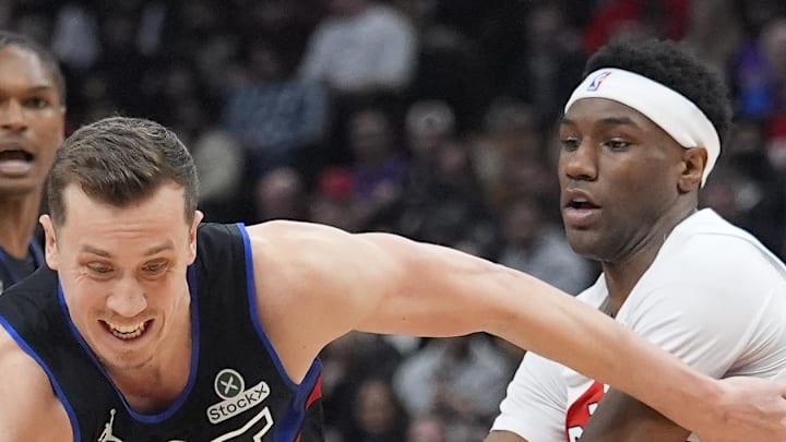 Detroit Pistons guard Duncan Robinson tries to dribble between Toronto Raptors guard Ja'Kobe Walter.