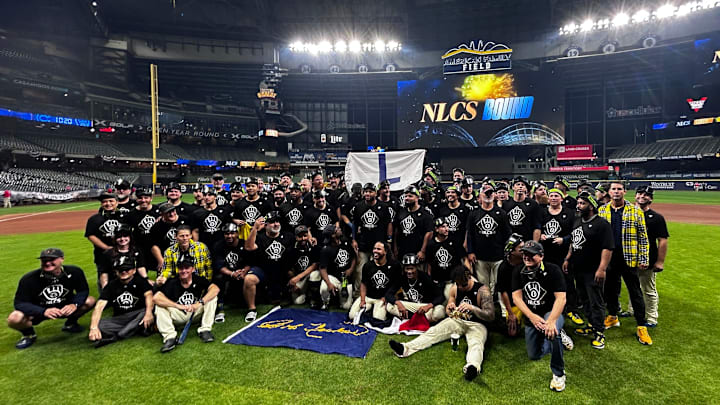 The Brewers celebrate with an 'L' flag on the field after beating the Cubs, 3 games to 2, in the 2025 National League Division Series