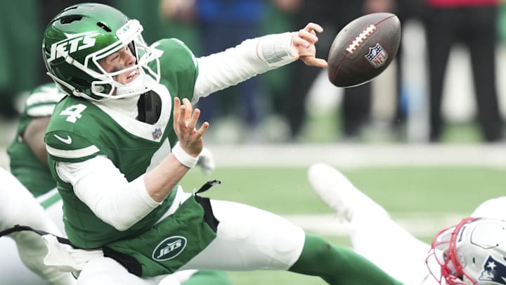 New York Jets quarterback Brady Cook (4) gets the ball off for an incomplete pass as he is tackled by New England Patriots linebacker Anfernee Jennings (33) during the second half of the game at MetLife Stadium.