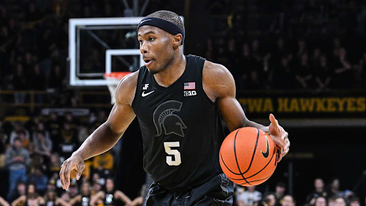 Mar 6, 2025; Iowa City, Iowa, USA; Michigan State Spartans guard Tre Holloman (5) controls the ball as Iowa Hawkeyes forward Payton Sandfort (20) defends during the first half at Carver-Hawkeye Arena. Mandatory Credit: Jeffrey Becker-Imagn Images