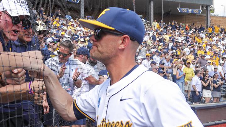 Jun 5, 2026; Morgantown, WV, USA; West Virginia Mountaineers head coach Steve Sabins celebrates with Pat McAfee in the stands after defeating the Cal Poly Mustangs at Kendrick Family Ballpark. Mandatory Credit: Ben Queen-Imagn Images