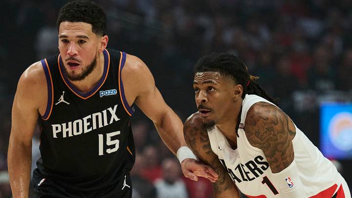 Oct 21, 2026; Portland, Oregon, USA; Phoenix Suns guard Devin Booker (15) holds back Portland Trail Blazers guard Ja Morant (1) during the first half at Moda Center. Mandatory Credit: Troy Wayrynen-Imagn Images