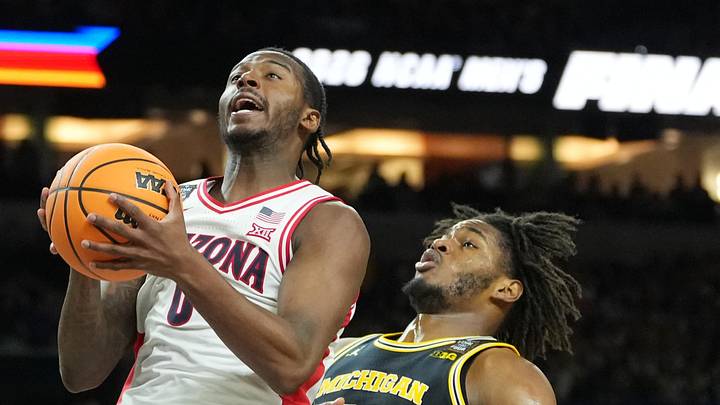 Arizona Wildcats guard Jaden Bradley (0) shoots against Michigan Wolverines forward Morez Johnson Jr. (21) in the second half during a semifinal of the Final Four of the men's 2026 NCAA Tournament at Lucas Oil Stadium.