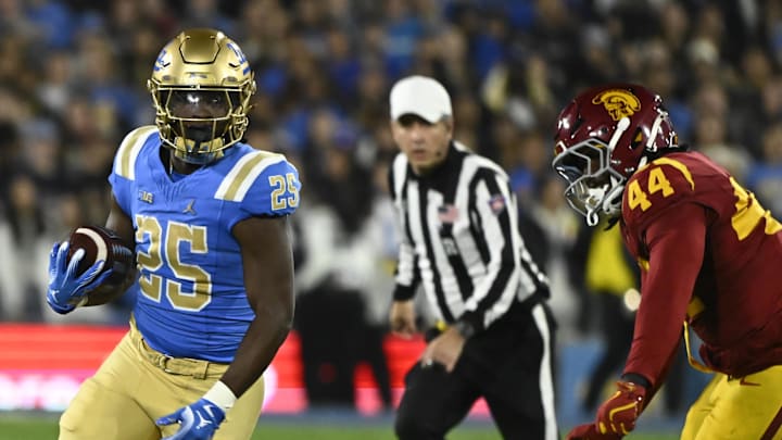 Nov 23, 2024; Pasadena, California, USA; UCLA Bruins running back T.J. Harden (25) runs past USC Trojans defensive end Sam Greene (44) during the first quarter at Rose Bowl. Mandatory Credit: Robert Hanashiro-Imagn Images Nov 23, 2024; Pasadena, California, USA; UCLA Bruins running back T.J. Harden (25) runs past USC Trojans defensive end Sam Greene (44) during the first quarter at Rose Bowl. Mandatory Credit: Robert Hanashiro-Imagn Images