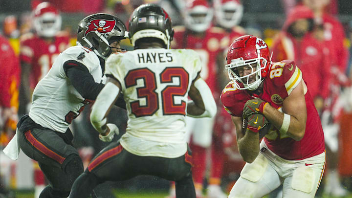 Nov 4, 2024; Kansas City, Missouri, USA; Kansas City Chiefs tight end Travis Kelce (87) runs with the ball against Tampa Bay Buccaneers safety Josh Hayes (32) and safety Antoine Winfield Jr. (31) during overtime at GEHA Field at Arrowhead Stadium. Mandatory Credit: Jay Biggerstaff-Imagn Images