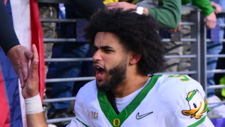 Nov 29, 2025; Seattle, Washington, USA; Oregon Ducks quarterback Dante Moore (5) celebrates with fans after Oregon defeated the Washington Huskies at Husky Stadium. Nov 29, 2025; Seattle, Washington, USA; Oregon Ducks quarterback Dante Moore (5) celebrates with fans after Oregon defeated the Washington Huskies at Husky Stadium.
