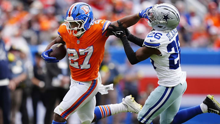 Oct 26, 2025; Denver, Colorado, USA; Denver Broncos running back J.K. Dobbins (27) runs against Dallas Cowboys cornerback DaRon Bland (26) in the first half at Empower Field at Mile High. 