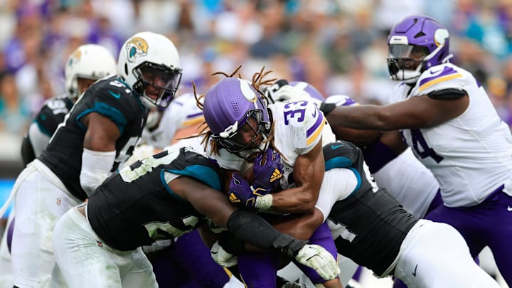 Minnesota Vikings running back Aaron Jones (33), center, is sandwiched between Jacksonville Jaguars linebacker Foyesade Oluokun (23), left, and defensive end Travon Walker (44) during the third quarter of an NFL football matchup Sunday, Nov. 10, 2024 at Everbank Stadium in Jacksonville, Fla. Jones left the game after an apparent injury on the play. The Vikings defeated the Jaguars 12-7. [Corey Perrine/Florida Times-Union]