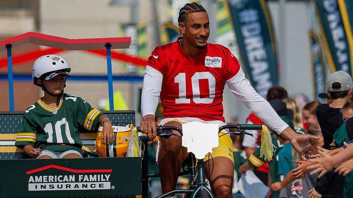 Green Bay Packers quarterback Jordan Love slaps hands with fans as he rides a bicycle to training camp last year. Green Bay Packers quarterback Jordan Love slaps hands with fans as he rides a bicycle to training camp last year.