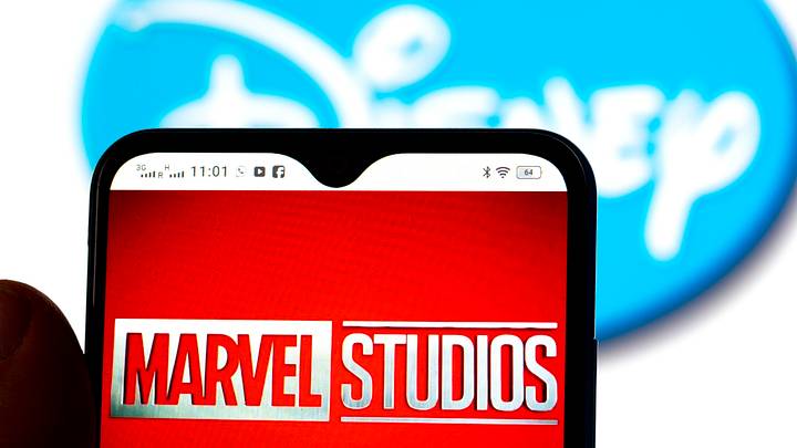 In this photo illustration, the Marvel Studios logo is seen displayed on a smartphone screen with a Disney logo in the background In this photo illustration, the Marvel Studios logo is seen displayed on a smartphone screen with a Disney logo in the background