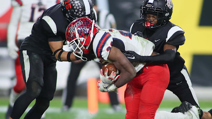 Aliquippa's QaLil Goode (14), Gavin Wilcox (13), and Arison Walker (15) attempt to hold back McKeesport's Kemon Spell (20) from scoring a touchdown during the second half of the WPIAL 4A Championship game Friday evening at Acrisure Stadium in Pittsburgh, PA.