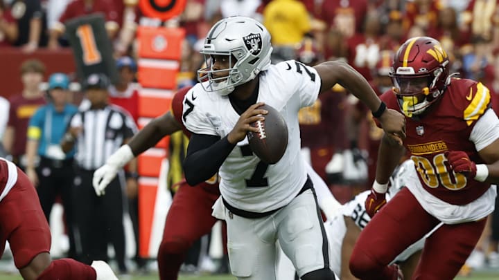 Sep 21, 2025; Landover, Maryland, USA; Las Vegas Raiders quarterback Geno Smith (7) scrambles from Washington Commanders defensive end Javontae Jean-Baptiste (90) during the third quarter at Northwest Stadium. Mandatory Credit: Geoff Burke-Imagn Images