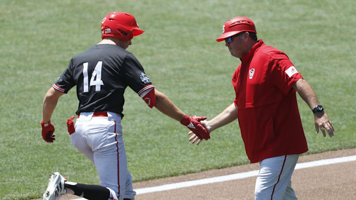 Jun 19, 2021; Omaha, Nebraska, USA;  NC State Wolfpack left fielder Jonny Butler (14) is congratulated by the third base coach after hitting a home run against the Stanford Cardinal at TD Ameritrade Park. Mandatory Credit: Bruce Thorson-Imagn Images