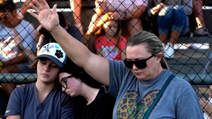 Community members pray during a prayer vigil for softball players and coaches involved in the Minco bus crash at the Minco softball field in Minco, Okla., Tuesday, Sept. 9, 2025.
