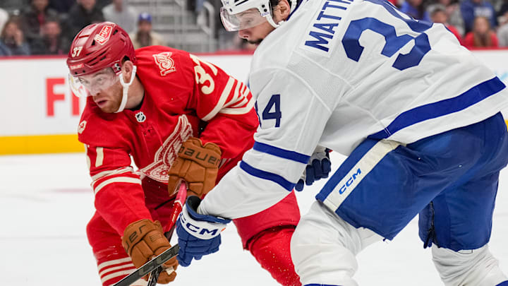 Detroit Red Wing forwards Andrew Copp (18) and J.T. Compher (37) battle Toronto Maple Leafs forward Auston Matthews (34) for the puck.