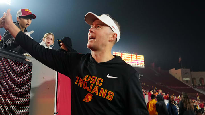 Nov 29, 2025; Los Angeles, California, USA; Southern California Trojans head coach Lincoln Riley celebrates with fans after the game against the UCLA Bruins at United Airlines Field at Los Angeles Memorial Coliseum. Mandatory Credit: Kirby Lee-Imagn Images