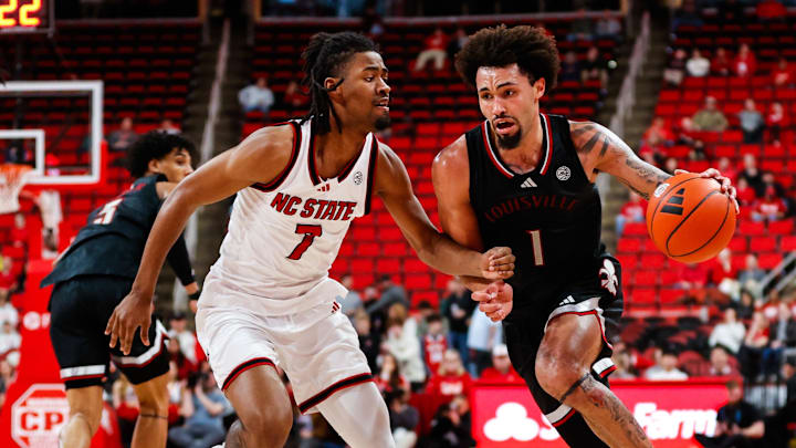 Feb 12, 2025; Raleigh, North Carolina, USA; Louisville Cardinals guard J'Vonne Hadley (1) dribbles with the ball guarded by North Carolina State Wolfpack guard Bryce Heard (7) during the second half of the game at Lenovo Center. Mandatory Credit: Jaylynn Nash-Imagn Images