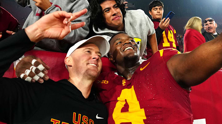 Nov 29, 2025; Los Angeles, California, USA; Southern California Trojans head coach Lincoln Riley (right) and defensive tackle Jahkeem Stewart (4) pose with fans after the game against the UCLA Bruins at United Airlines Field at Los Angeles Memorial Coliseum. Mandatory Credit: Kirby Lee-Imagn Images