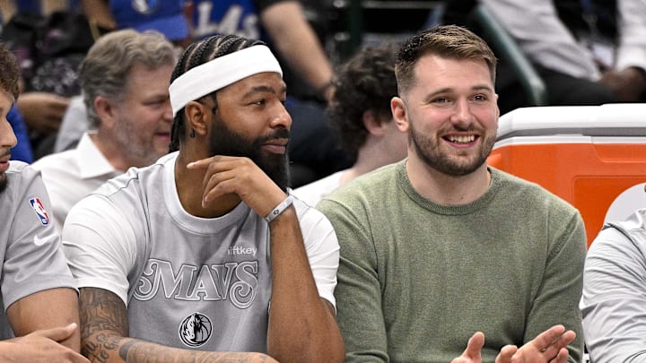 Nov 27, 2024; Dallas, Texas, USA; (from left) Dallas Mavericks center Dereck Lively II and forward Markieff Morris and guard Luka Doncic sit on the team bench during the second quarter of the game between the Mavericks and the New York Knicks at the American Airlines Center. Mandatory Credit: Jerome Miron-Imagn Images