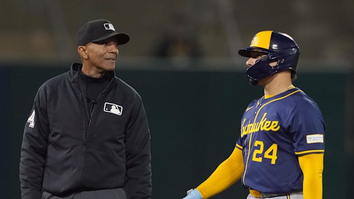 Aug 23, 2024; Oakland, California, USA; Second base umpire CB Bucknor (left) talks with Milwaukee Brewers catcher William Contreras (24) during the ninth inning against the Oakland Athletics at Oakland-Alameda County Coliseum. Mandatory Credit: Darren Yamashita-Imagn Images