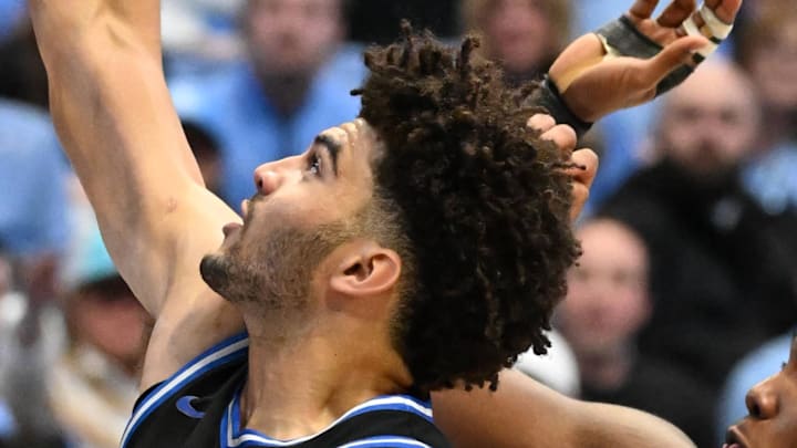 Feb 7, 2026; Chapel Hill, North Carolina, USA; Duke Blue Devils forward Cameron Boozer (12) shoots as North Carolina Tar Heels guard Kyan Evans (0) and forward Jarin Stevenson (15) and forward Jonathan Powell (11) defend in the first  half at Dean E. Smith Center. Mandatory Credit: Bob Donnan-Imagn Images