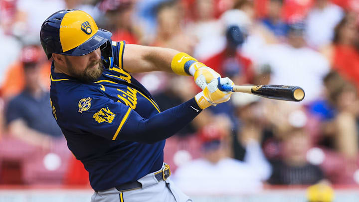 Jun 4, 2025; Cincinnati, Ohio, USA; Milwaukee Brewers first baseman Rhys Hoskins (12) hits a single in the fourth inning against the Cincinnati Reds at Great American Ball Park. Mandatory Credit: Katie Stratman-Imagn Images