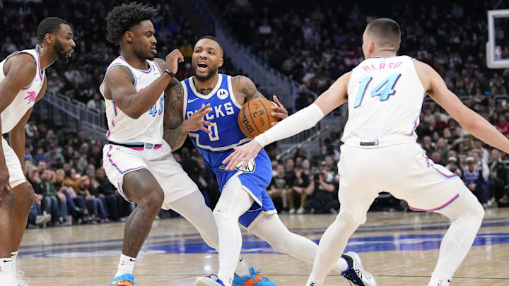 Feb 23, 2025; Milwaukee, Wisconsin, USA;  Milwaukee Bucks guard Damian Lillard (0) drives for the basket between Miami Heat guard Davion Mitchell (45) and guard Tyler Herro (14) during the second quarter at Fiserv Forum. Mandatory Credit: Jeff Hanisch-Imagn Images