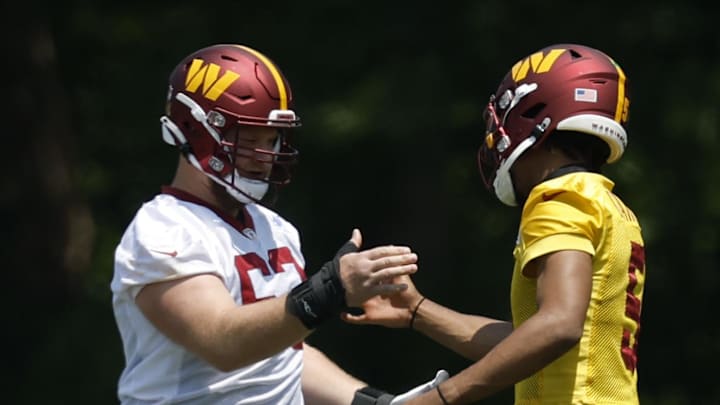 Jun 10, 2025; Ashburn, VA, USA; Washington Commanders center Tyler Biadasz (63) shakes hands with Commanders quarterback Jayden Daniels (5) during drills on day one of minicamp at Commanders Park. Mandatory Credit: Geoff Burke-Imagn Images