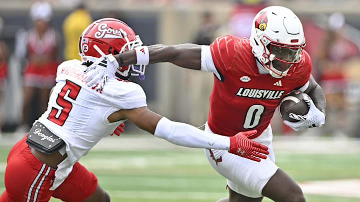 Aug 31, 2024; Louisville, Kentucky, USA;  Louisville Cardinals wide receiver Chris Bell (0) runs the ball against Austin Peay Governors defensive back Sammy Anderson Jr. (5) during the first quarter at L&N Federal Credit Union Stadium. Mandatory Credit: Jamie Rhodes-Imagn Images