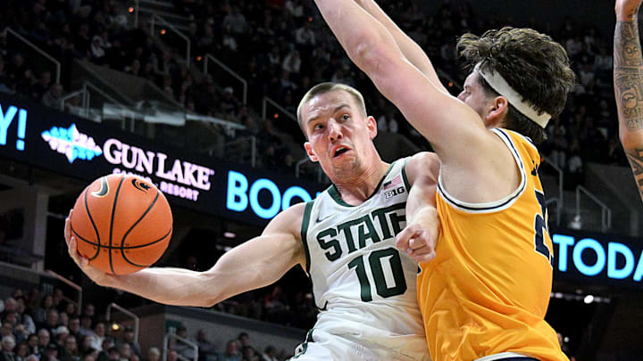 Dec 16, 2025; East Lansing, Michigan, USA; Michigan State Spartans guard Denham Wojcik (10) passes the ball around Toledo Rockets center Austin Parks (25) during the second half at Jack Breslin Student Events Center. Mandatory Credit: Dale Young-Imagn Images Dec 16, 2025; East Lansing, Michigan, USA; Michigan State Spartans guard Denham Wojcik (10) passes the ball around Toledo Rockets center Austin Parks (25) during the second half at Jack Breslin Student Events Center. Mandatory Credit: Dale Young-Imagn Images