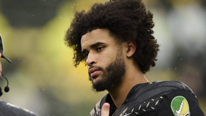 Oct 25, 2025; Eugene, Oregon, USA; Oregon Ducks quarterback Dante Moore (5) talks to officials during warm ups before a game against the Wisconsin Badgers at Autzen Stadium. The Ducks are wearing uniforms celebrating the Grateful Dead. Mandatory Credit: Troy Wayrynen-Imagn Images Oct 25, 2025; Eugene, Oregon, USA; Oregon Ducks quarterback Dante Moore (5) talks to officials during warm ups before a game against the Wisconsin Badgers at Autzen Stadium. The Ducks are wearing uniforms celebrating the Grateful Dead. Mandatory Credit: Troy Wayrynen-Imagn Images