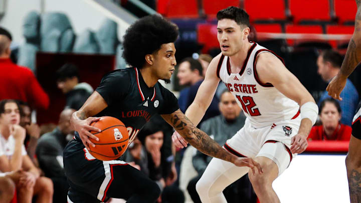 Feb 12, 2025; Raleigh, North Carolina, USA; Louisville Cardinals guard Chucky Hepburn (24) dribbles the ball while guarded by North Carolina State Wolfpack guard Michael O'Connell (12) during the first half of the game at Lenovo Center. 